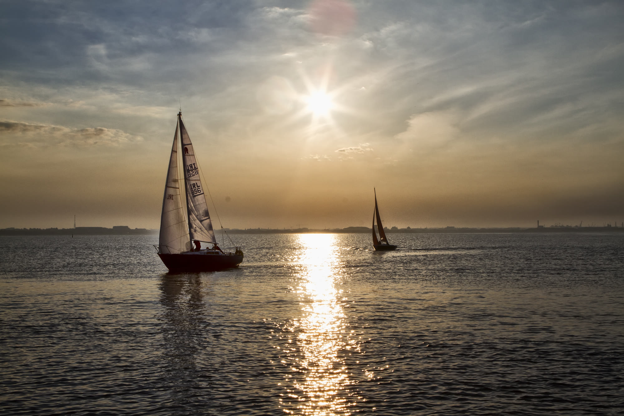 Sailboats crossing Dublin Bay at sunset