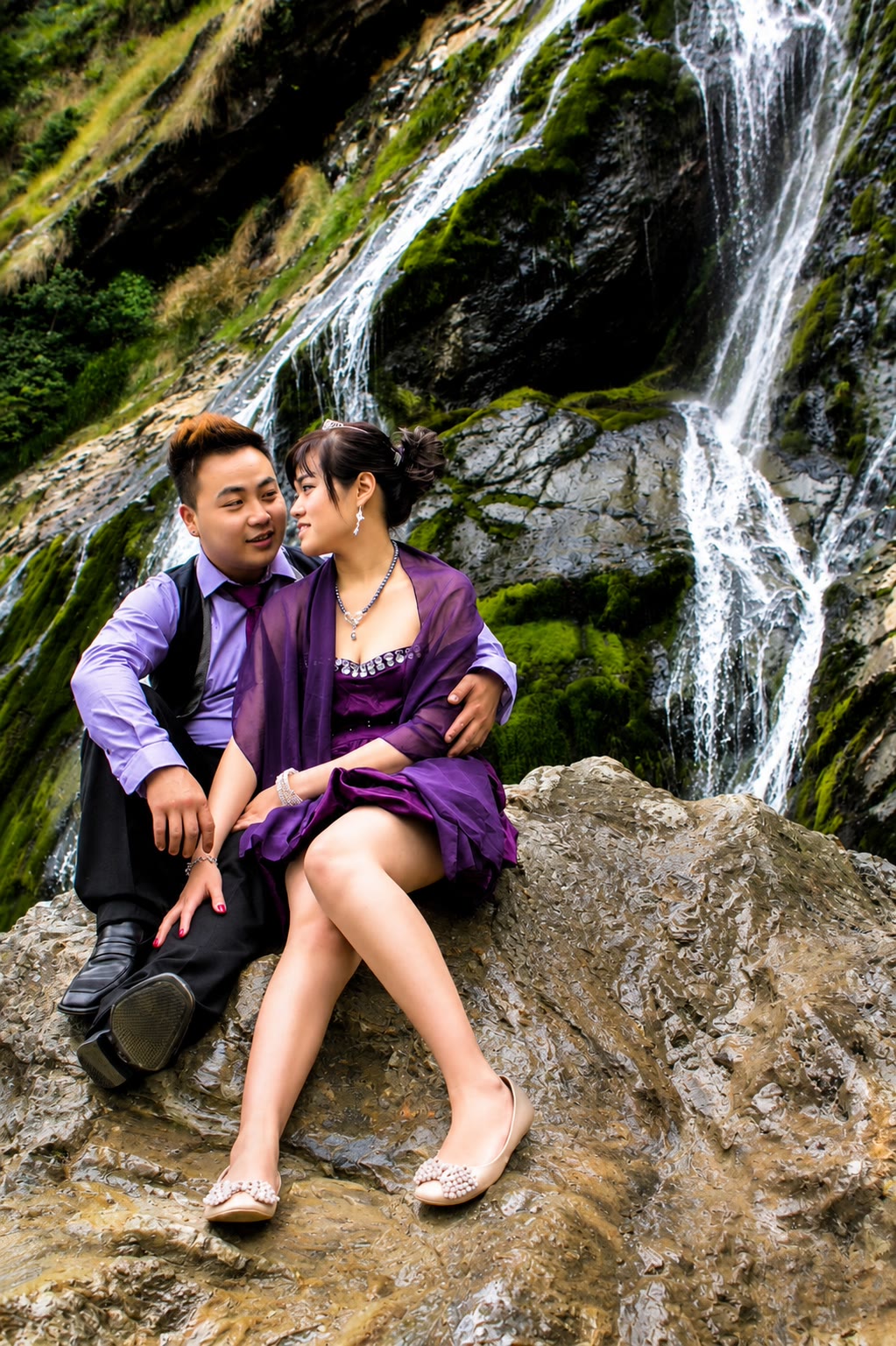 Kenzo and May seated together beside a waterfall